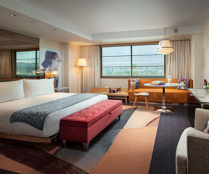 Luxurious hotel room with a plush bed, elegant couch, and a window.